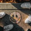 smiley paint on gray ground in front of people