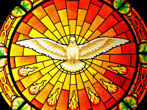 Stained glass window of dove in center of circle with descending flames of fire